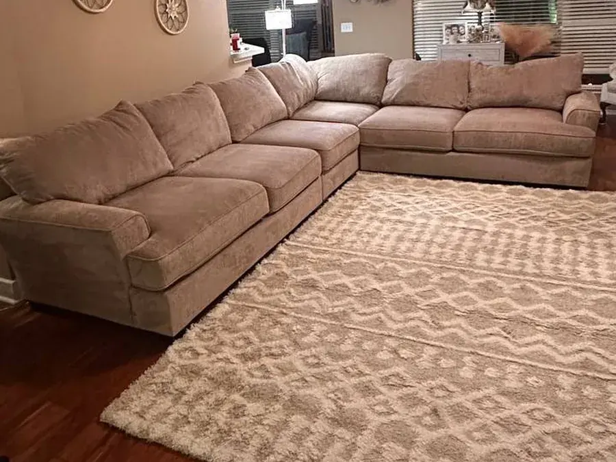 The same beige sectional after cleaning and water-repellent protection, with a new rug