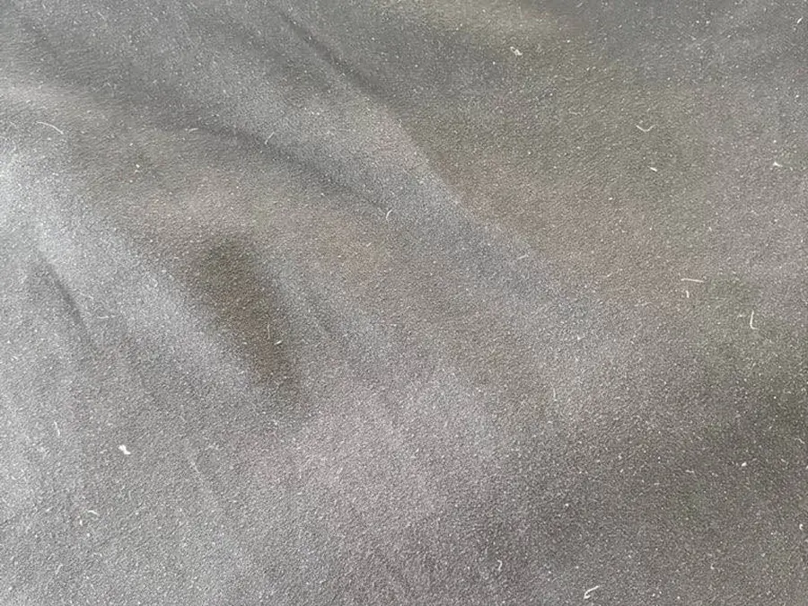 Close-up of a food stain and lint on the black fabric before cleaning