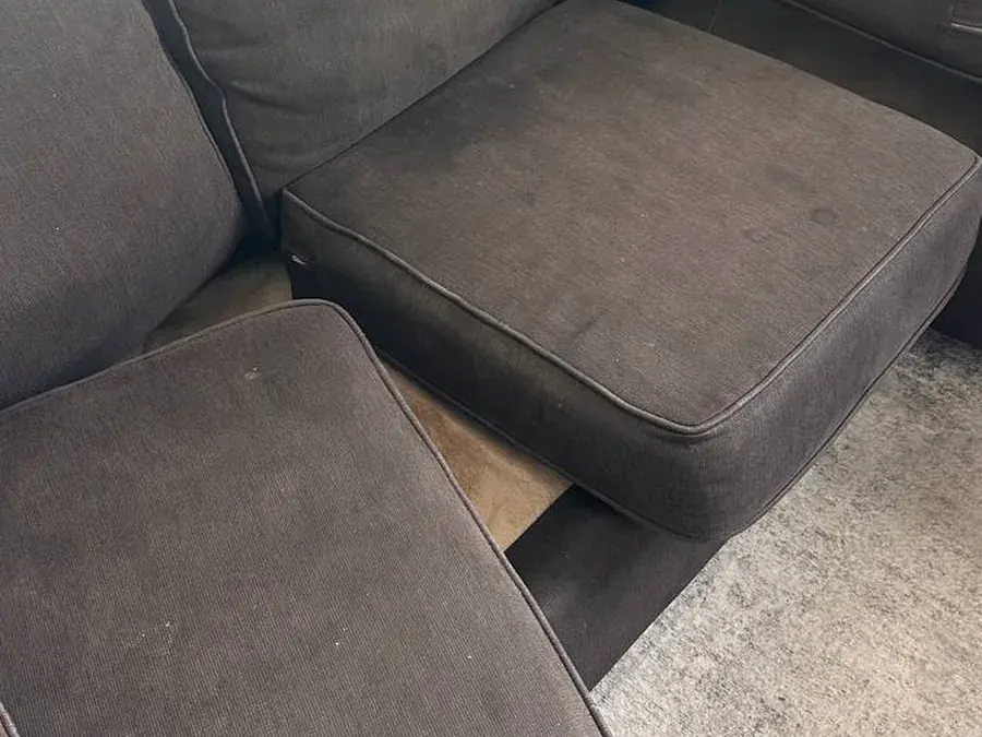 Dark brown sectional seat cushions with dirt, food and drink spots before cleaning in a Houston home