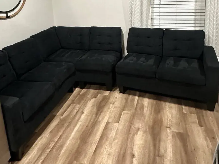 The same black tufted sectional after cleaning, a deep even black again