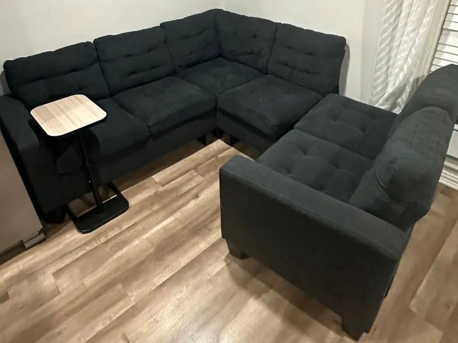 Black tufted fabric sectional before cleaning, faded to a dull charcoal with food and drink stains, in a Houston home