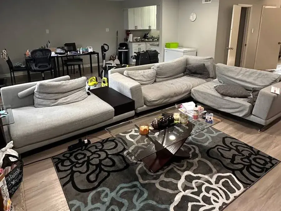 Large gray modern sectional in a Houston apartment before cleaning