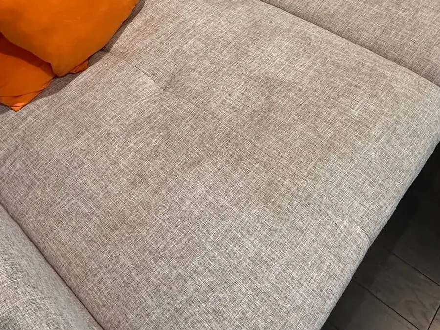 Light gray woven sectional seat cushion with dirt, food and drink stains before cleaning in a Houston home