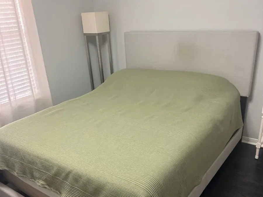 Light upholstered bed headboard with a large coffee stain before cleaning in a Houston bedroom