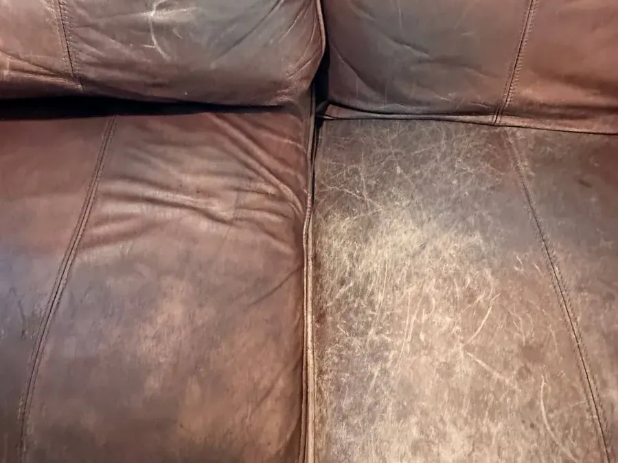 Close-up of worn leather seat cushions with scuffs, dark soil and stains before cleaning