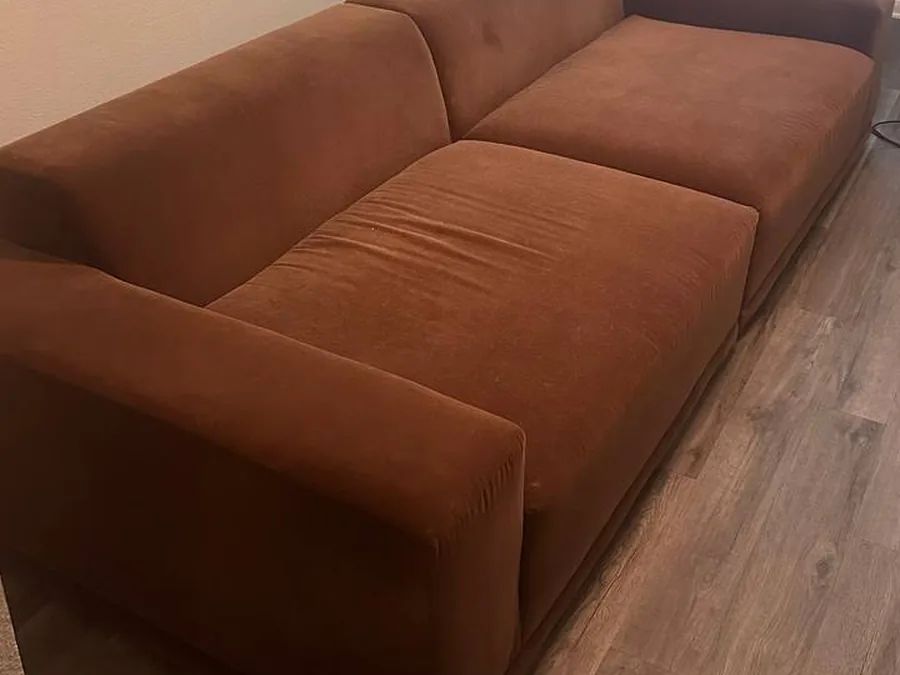 Rust-colored fabric sofa before cleaning, dulled by dog hair and soil, in a Houston apartment