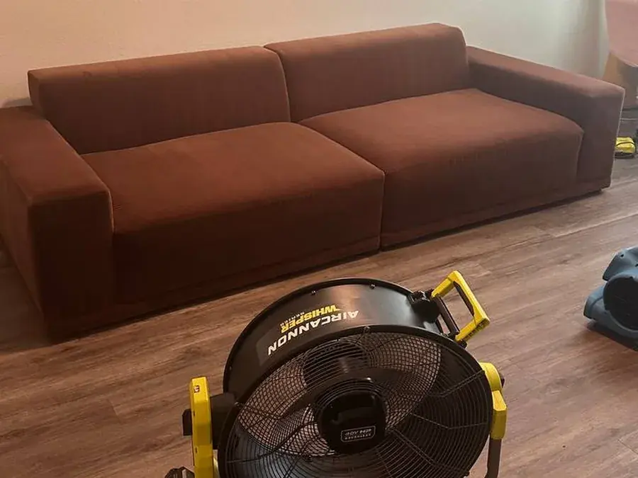 The same sofa drying after deep cleaning, with an air mover in front