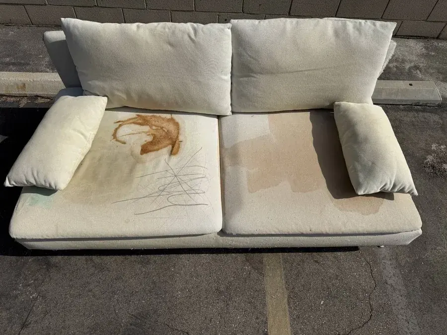 Cream fabric loveseat before cleaning, covered in oil, coffee, pizza, food and marker stains