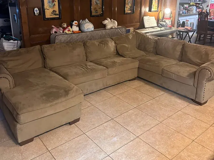 Large tan microsuede sectional with chaise before cleaning, soiled with dirt and oily stains, in a Houston living room