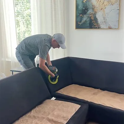 Scrubbing a dark sectional sofa with a power brush in a Houston home